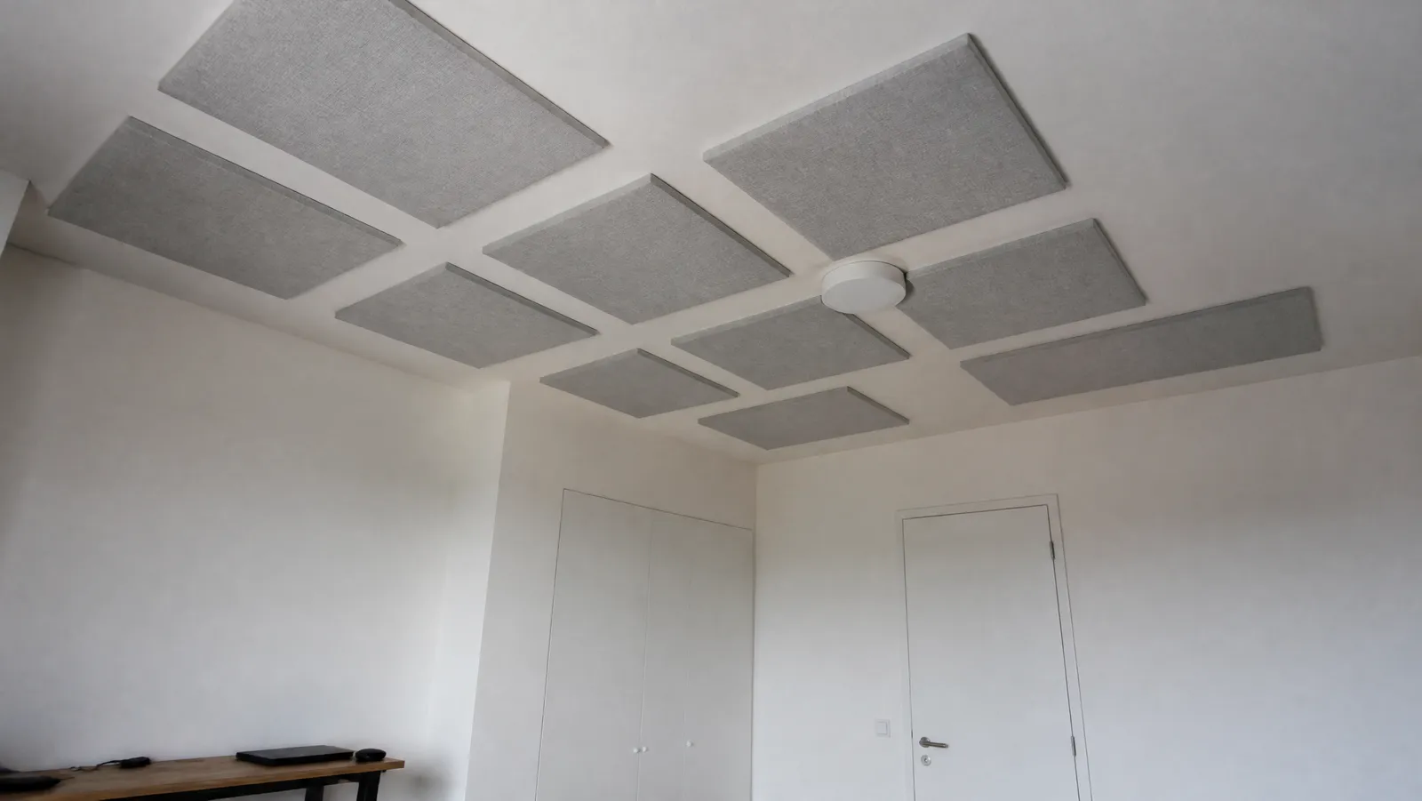 Grey fabric-wrapped acoustic panels mounted in a grid on a white apartment ceiling
