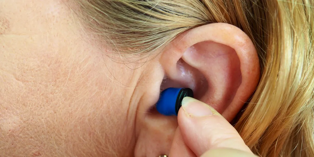 A pair of soft silicone earplugs on a bedside table in a city apartment